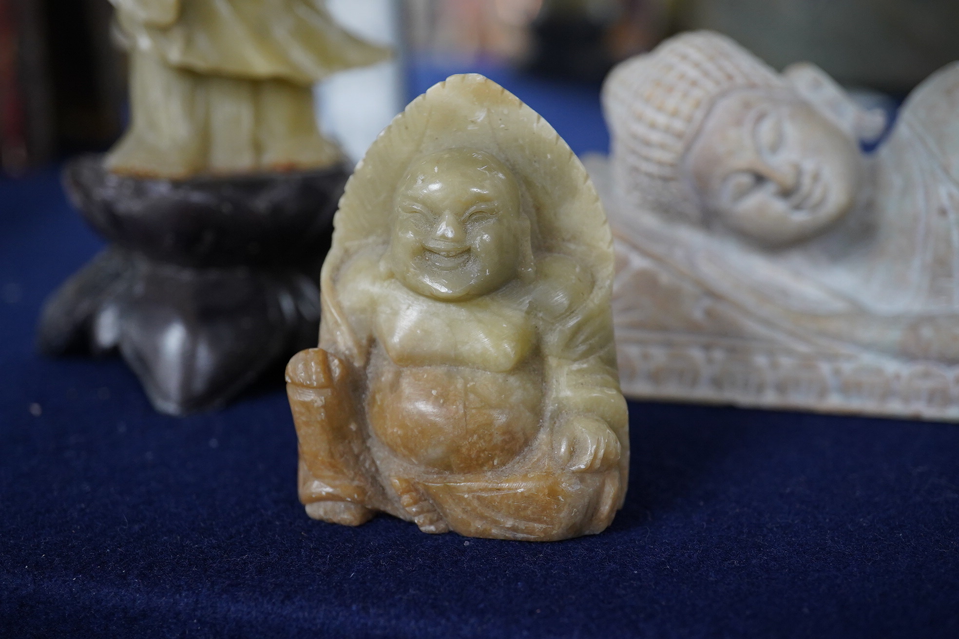 A carved stone reclining buddha, a Chinese deity and a seated buddha, largest 20cm wide. Condition - fair to good